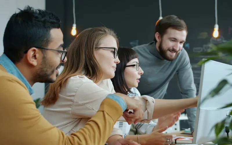 A team collaborating around a computer screen