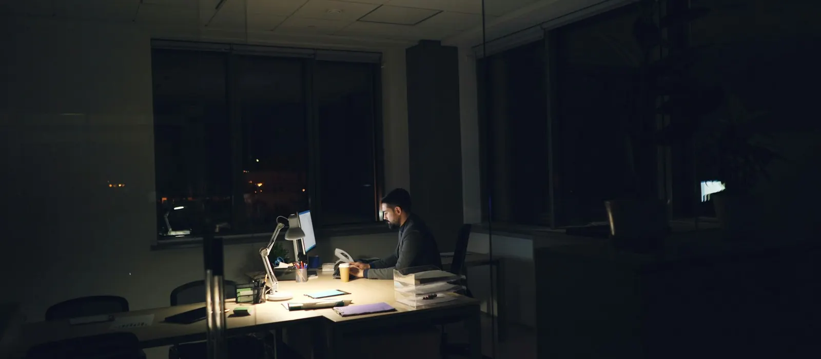 A man working late at a dimly lit office desk