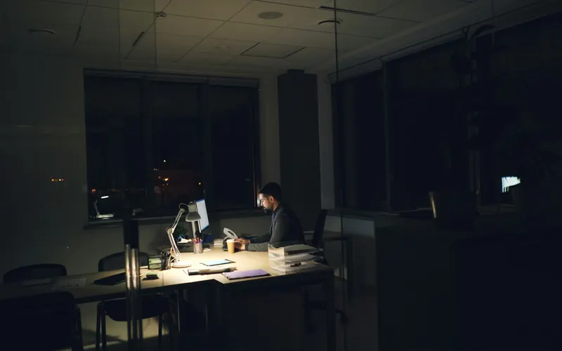 A man working late at a dimly lit office desk
