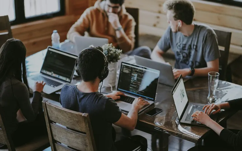 A small team working around a shared table with laptops