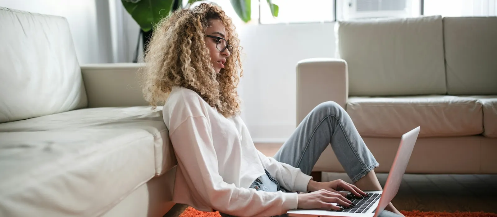 A woman sitting on the floor at home using a laptop