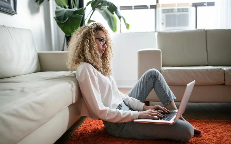 A woman sitting on the floor at home using a laptop