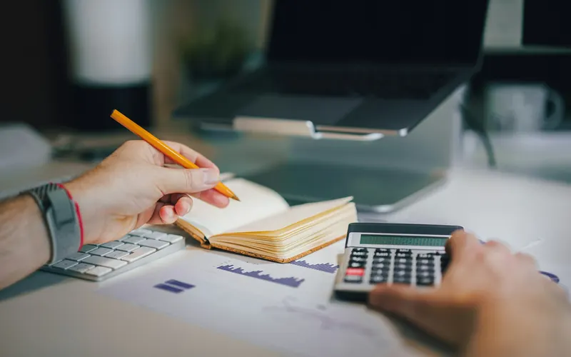 A person at a desk with a calculator and a notebook