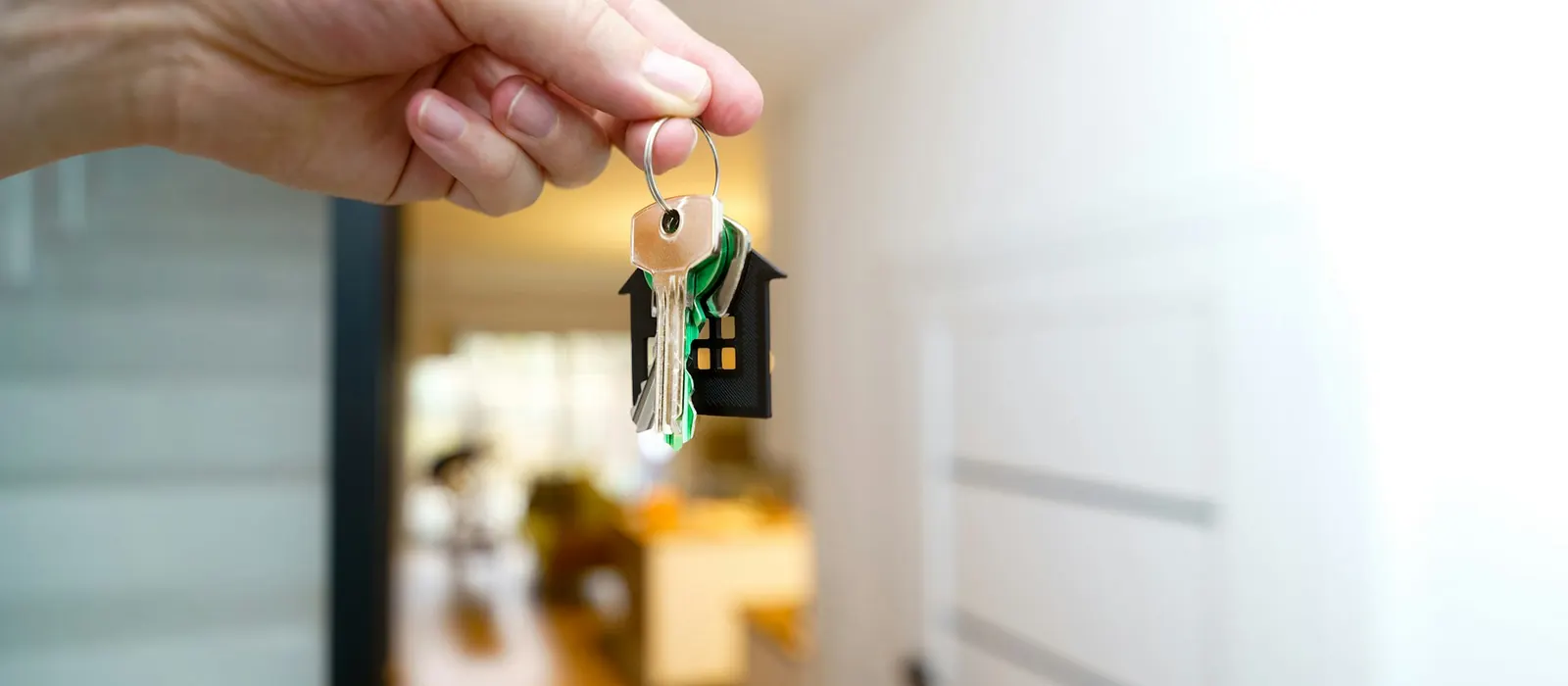 A hand holding house keys in front of a front door
