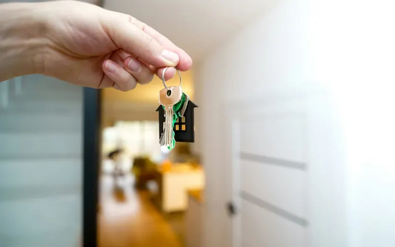 A hand holding house keys in front of a front door