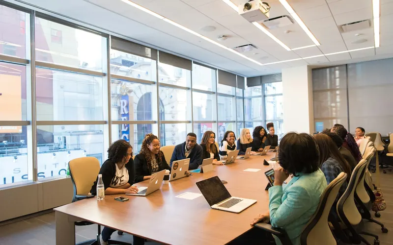 A sales team meeting around a wooden table with laptops