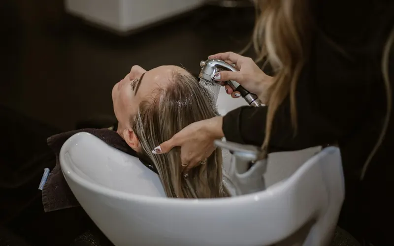 A stylist washing a client's hair at a salon basin
