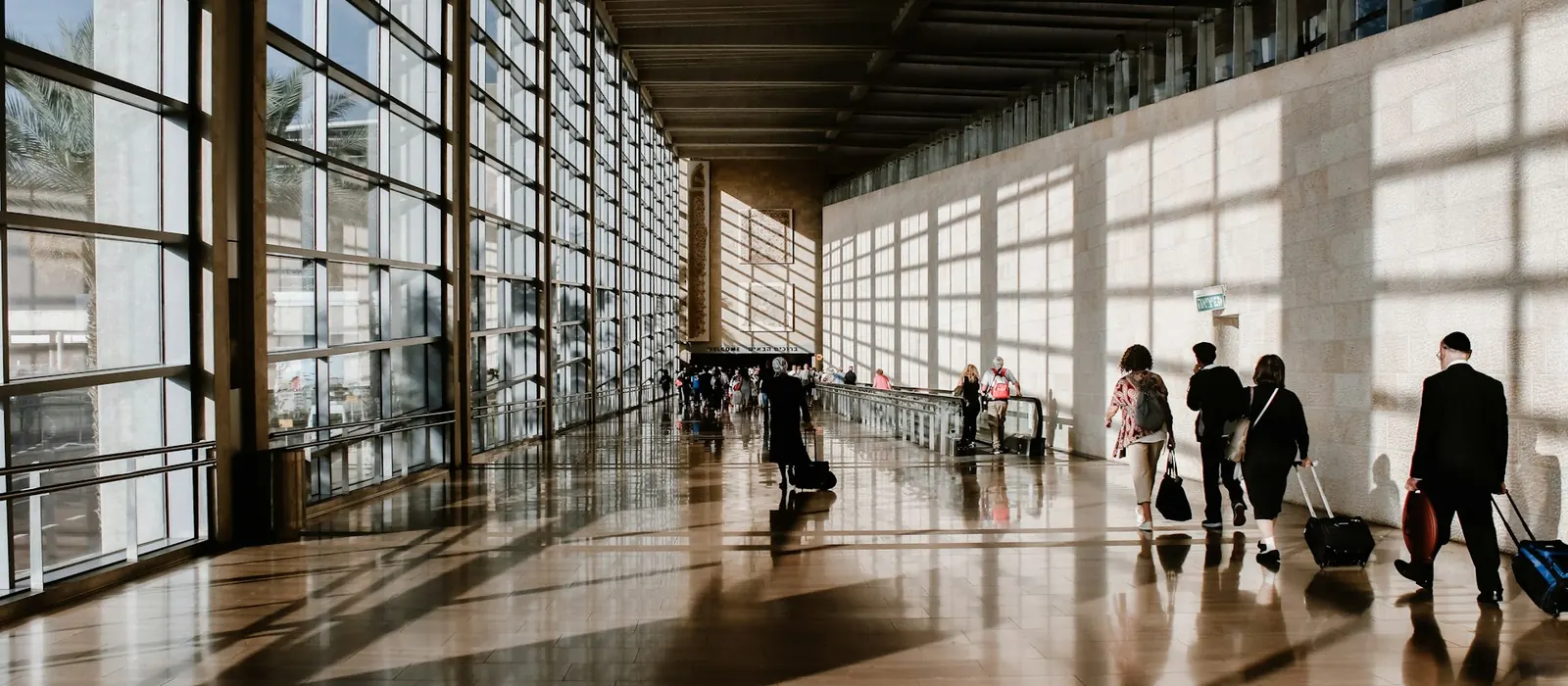People walking through a sunlit airport terminal