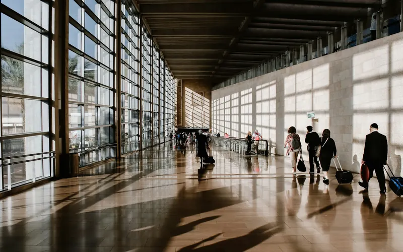 People walking through a sunlit airport terminal